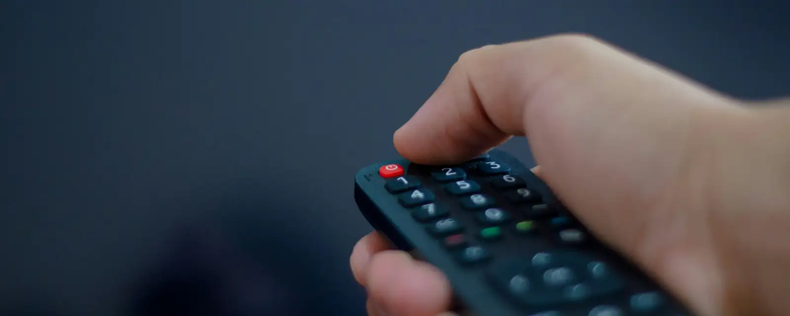 Mano con un control remoto frente a la tele