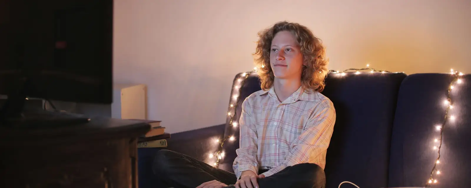 Joven en el sofá de su sala mirando la tele de noche
