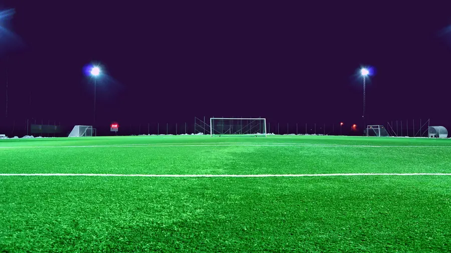 Cancha de fútbol iluminada de noche, vista en la pantalla de la tele