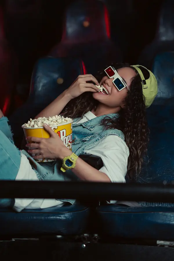 Mujer con lentes 3D comiendo palomitas en una sala de cine