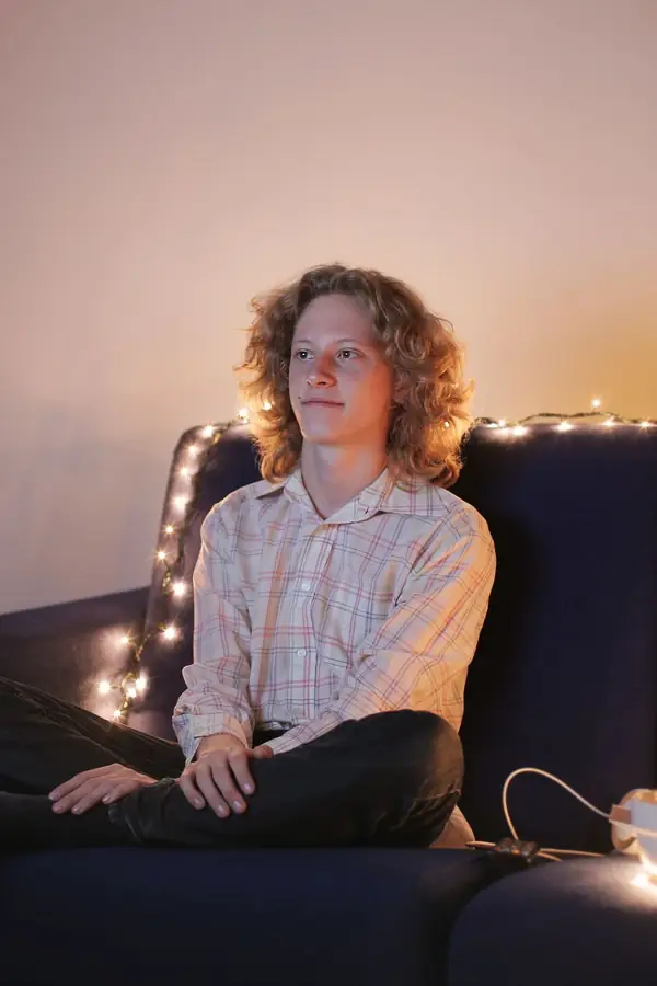 Joven sentado en un sofá mirando la tele en una sala con luces
